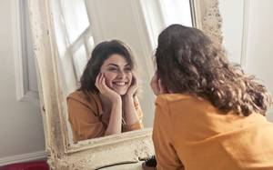 Une jeune fille se ragrde dans le miroir en souriant