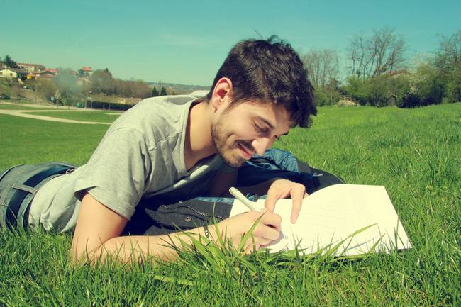 Homme allongé sur l'herbe en train d'écrire